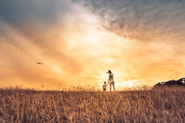 Mother and her baby boy watching a airplane flying in the sky.