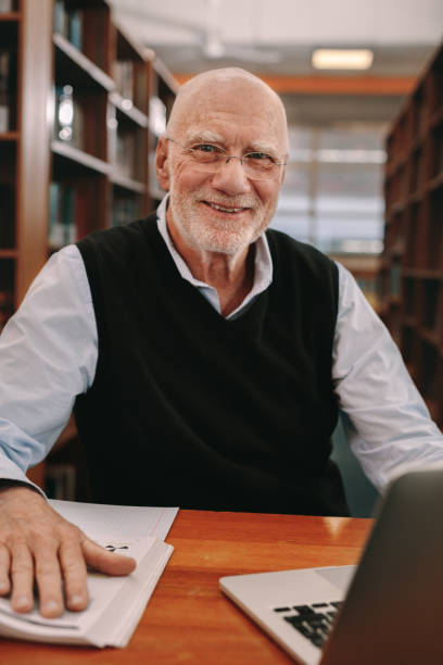 istock Cheerful senior man learning sitting at a library 1138715512