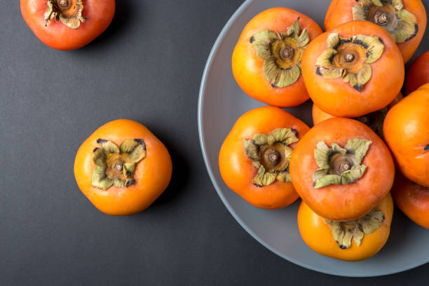 istock Delicious fresh persimmon fruits on black background. 1138715780