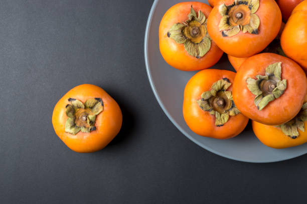 istock Delicious fresh persimmon fruits on black background. 1138715782