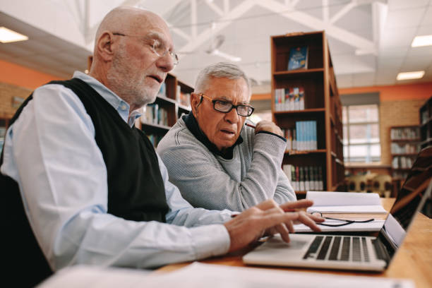 istock Senior gentlemen sitting together in library doing their coursework 1138716039