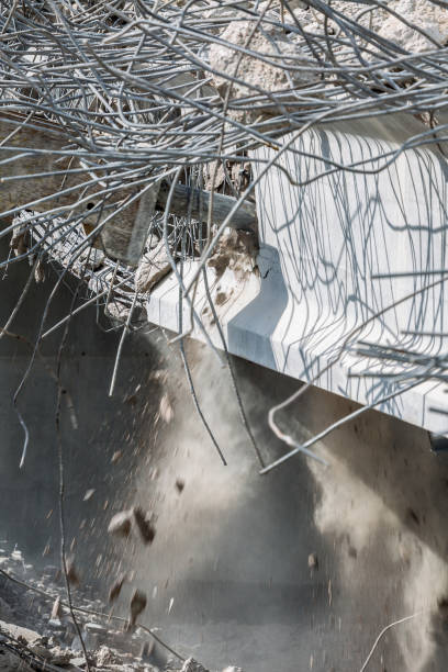 Professional demolition of reinforced concrete structures using industrial hydraulic hammer. Rods of metal fittings. Wreckage and crumbles of concrete.