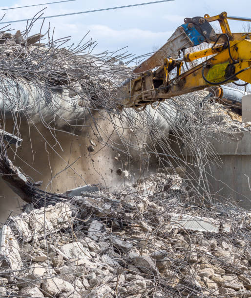 Professional demolition of reinforced concrete structures using industrial hydraulic hammer. Rods of metal fittings. Wreckage and crumbles of concrete.