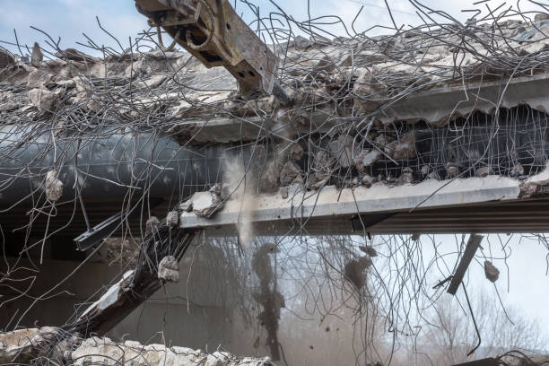 Professional demolition of reinforced concrete structures using industrial hydraulic hammer. Rods of metal fittings. Wreckage and crumbles of concrete.