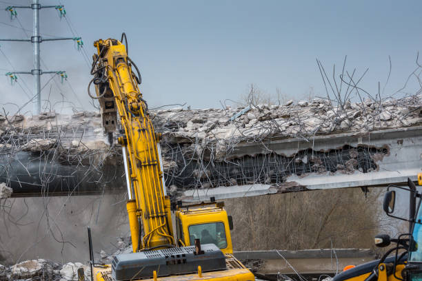 Professional demolition of reinforced concrete structures using industrial hydraulic hammer. Rods of metal fittings. Wreckage and crumbles of concrete.