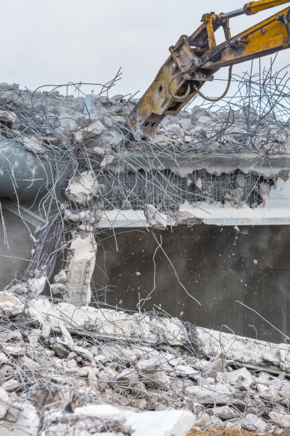istock Professional demolition of reinforced concrete structures using industrial hydraulic hammer. Rods of metal fittings. Wreckage and crumbles of concrete. 1138716182