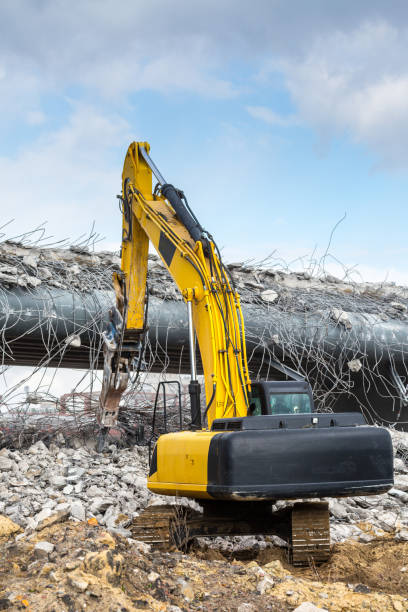 Professional demolition of reinforced concrete structures using industrial hydraulic hammer. Rods of metal fittings. Wreckage and crumbles of concrete. Professional demolition of reinforced concrete structures using industrial hydraulic hammer. Rods of metal fittings. Wreckage and crumbles of concrete. deconstruct stock pictures, royalty-free photos & images