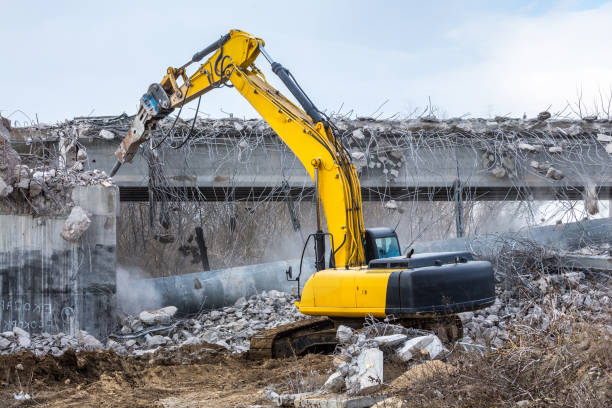 Professional demolition of reinforced concrete structures using industrial hydraulic hammer. Rods of metal fittings. Wreckage and crumbles of concrete.