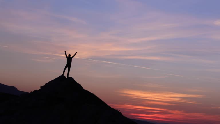 Silhouette of climber man success summit on the mountain peak