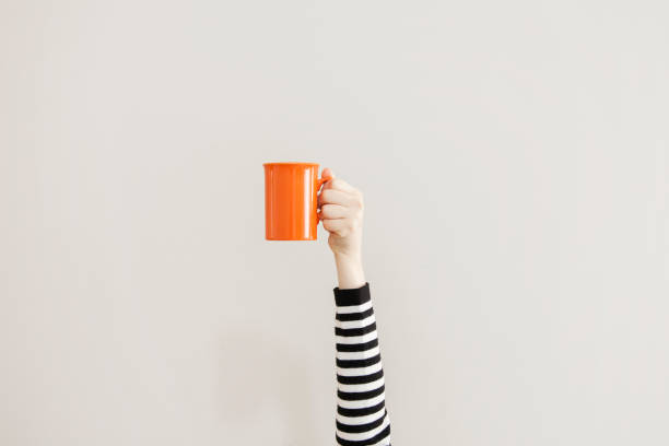 Arm raised up holding coffee cup stock photo