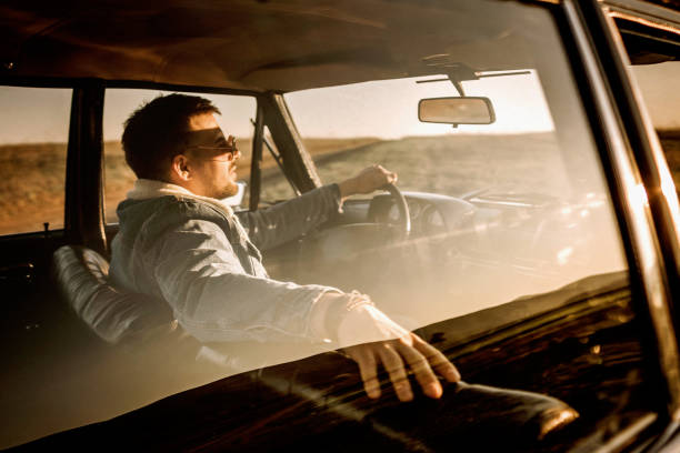 istock Handsome man driving car in sunset 1138720739
