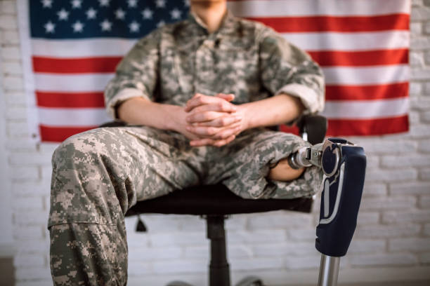 soldato irriconoscibile con gamba amputata seduta sulla sedia - depression sadness usa american flag foto e immagini stock