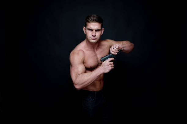 istock Shirtless muscular man holding a handgun 1138721995