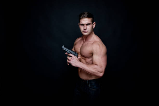 istock Shirtless muscular man holding a handgun 1138722091