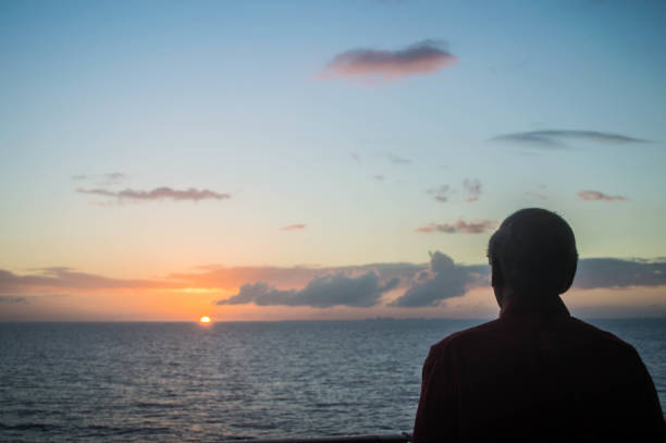 istock Man watching moody sky sunset aboard cruise ship on ocean 1138727403