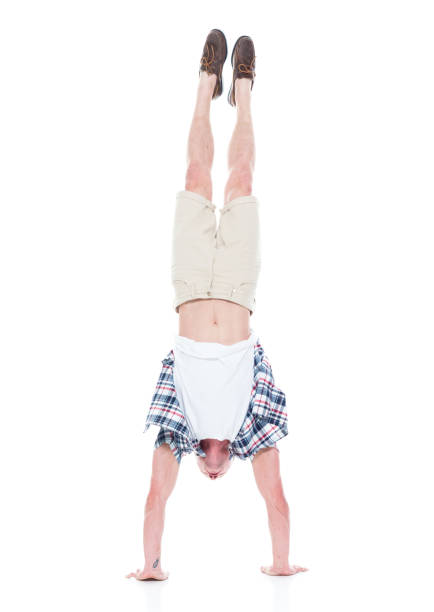 istock Handsome man in shirt and shorts is doing a handstand 1138729312