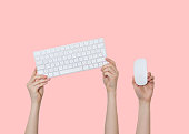 Raising hands with keyboard and mouse on pink background