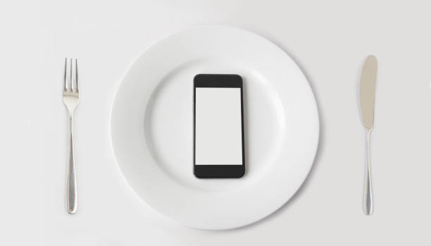 istock A smartphone with copy space on white plate with fork and knife. 1138740640
