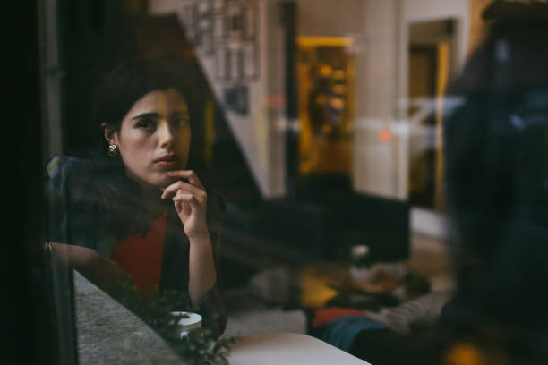 Vintage toned portrait of a young Latinx woman, sitting and relaxing in a cafe in downtown Los Angeles, drinking coffee, having an easy afternoon after work or studies.