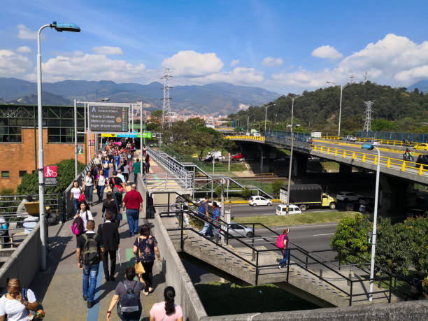 Medellin, Colombia, with detail of a bridges, roads, hills, and people Medellin, Colombia, with detail of a bridge with many people to access the subway system and metroplús, a busy avenue, a bridge for cars, and in the background a green hill with other parts of the city. metro medellin stock pictures, royalty-free photos & images