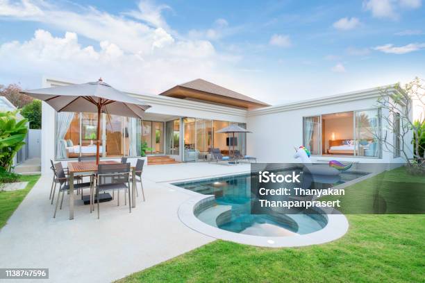 Home Or House Exterior Design Showing Tropical Pool Villa With Greenery Garden Sun Bed Umbrella Pool Towels And Colorful Floating Unicorn Stock Photo - Download Image Now