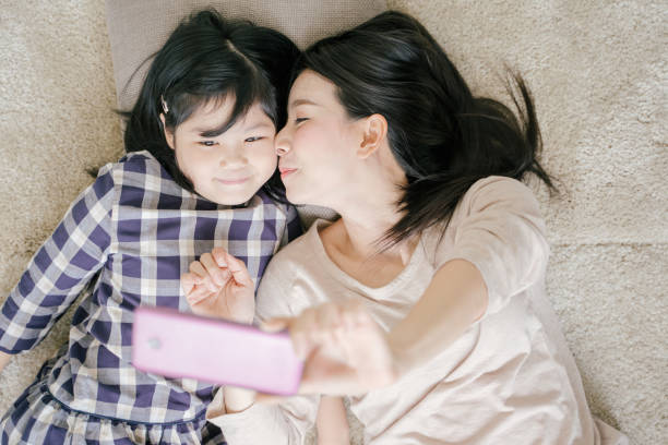 istock Mother is selfie with her little daughter using a smart phone camera while kissing daughter cheek 1138758544