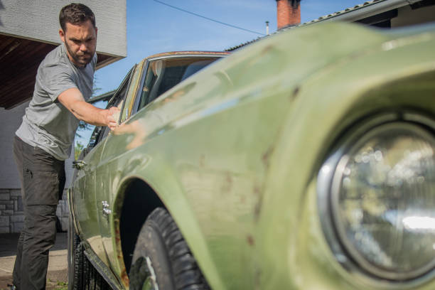 istock Man cleaning vintage car windows 1138769906