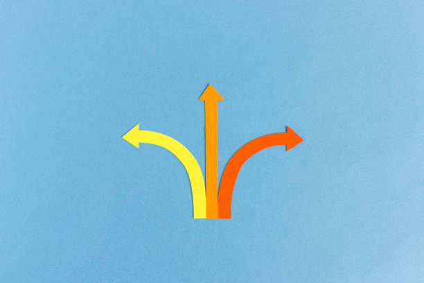 Minimalist cutout composition of yellow, red and orange arrows showing three different directions on blue background