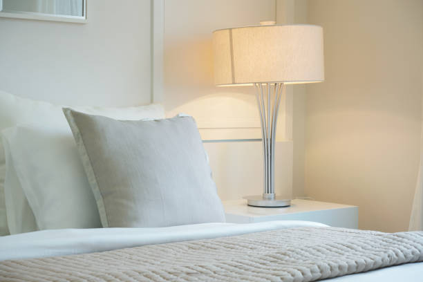 istock Beige color scheme bedding with white reading lamp in modern bedroom 1138782329