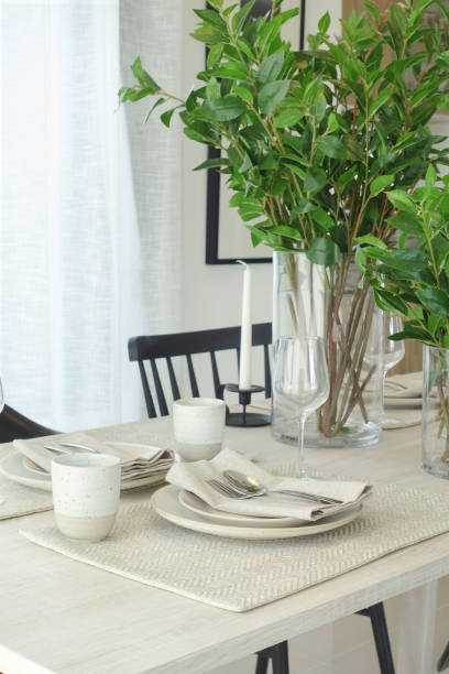 Earth tone style dining set with green leaves vase in background stock photo