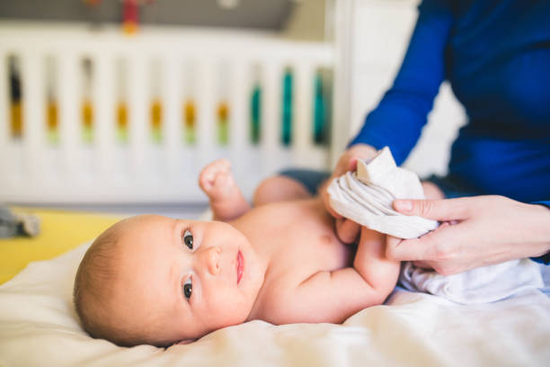 Mother putting diaper on her happy baby