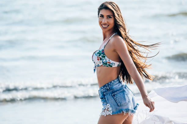 стильная кавказская улыбающаяся женщина в модной джинсовой пляжной одежде - side view walking swimwear fashion model стоковые фото и изображения