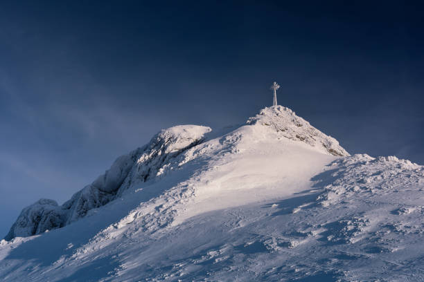 Snow covered cross on the mountain top Giewont. Polish national park
