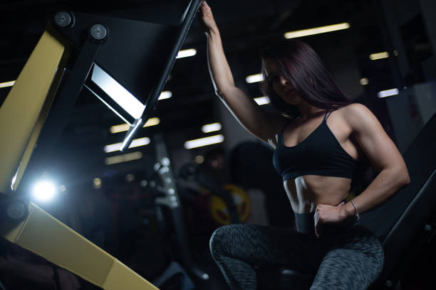 fille de remise en forme posant dans la salle de gym, exhibant son corps et relaxant après une séance d'entraînement - showing off muscular build the human body human muscle photos et images de collection