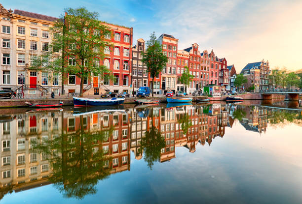 красивый закат амстердама. типичные старые голландские дома на мосту и каналах весной, нидерланды - amsterdam стоковые фото и изображения