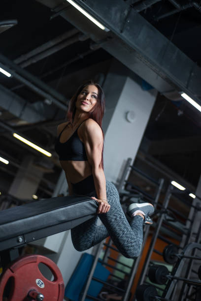 fille de remise en forme posant dans la salle de gym, exhibant son corps et relaxant après une séance d'entraînement - showing off muscular build the human body human muscle photos et images de collection