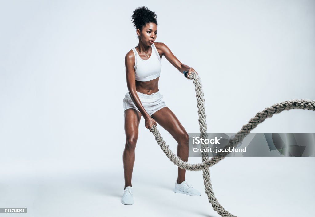 Athlete working out with battle ropes Fitness woman using training ropes for exercises. Athlete working out with battle ropes on white background. Exercising Stock Photo