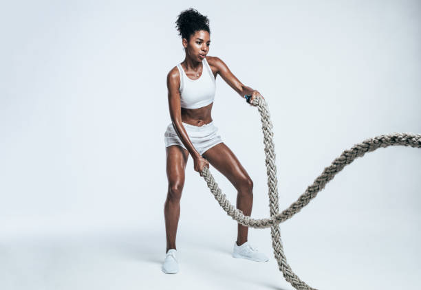 Athlete working out with battle ropes Fitness woman using training ropes for exercises. Athlete working out with battle ropes on white background. cross training photos stock pictures, royalty-free photos & images