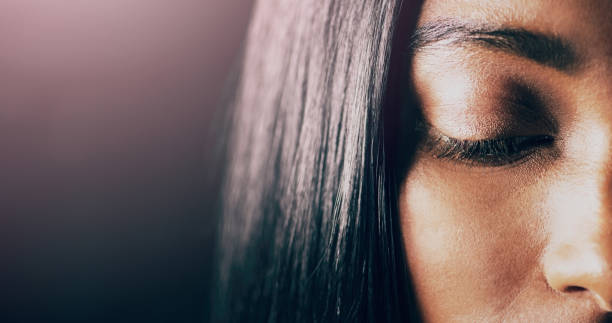 Closeup shot of a beautiful young woman posing with her eyes closed against a dark background