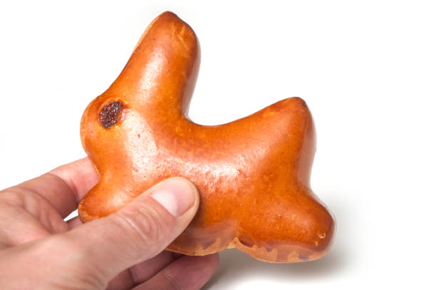 traditional  bun in shaped rabbit with dried raisin in hand on white background