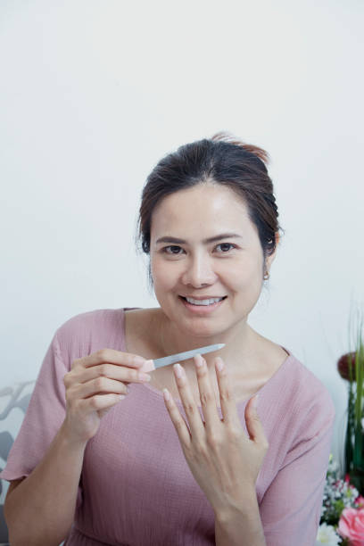 istock asian woman using nail buffer when doing manicure, polishing nails at home. 1138792718