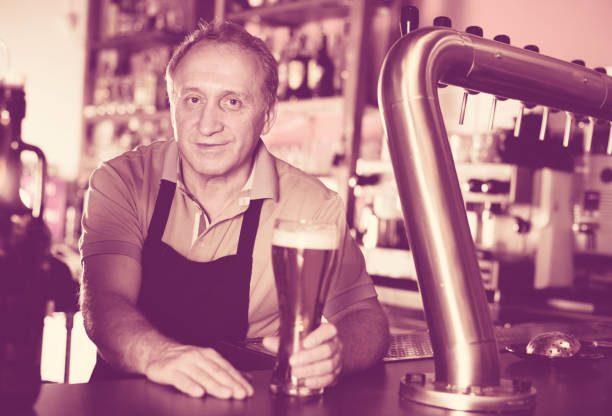 istock Smiling barman is offering unbottled beer to next client 1138792809