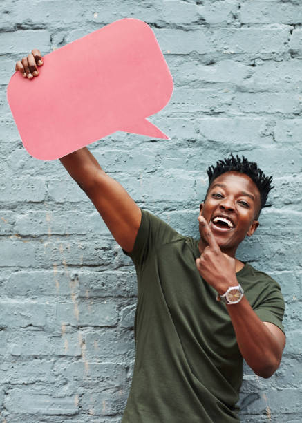 Cropped shot of a young man holding a speech bubble against a brick wall outside