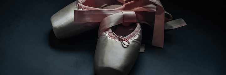 Pointe shoes ballet dance shoes with a bow of ribbons beautifully folded on a dark background
