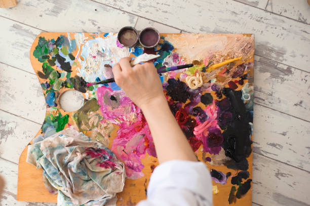 istock Young female student having classes at art studio, trying to mix different watercolors on cardboard. 1138801661