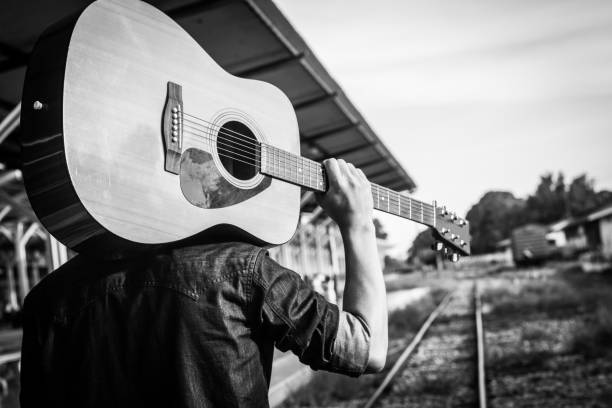 Guy with guitar on the railway road. Black and white photo