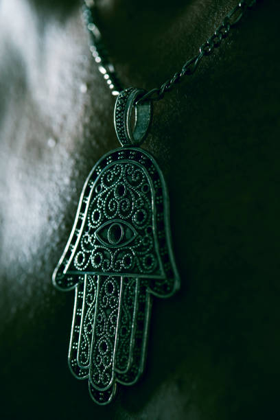 closeup of an old hamsa amulet, also known of the hand of fatima or the hand of mary, hanging from the neck of a man