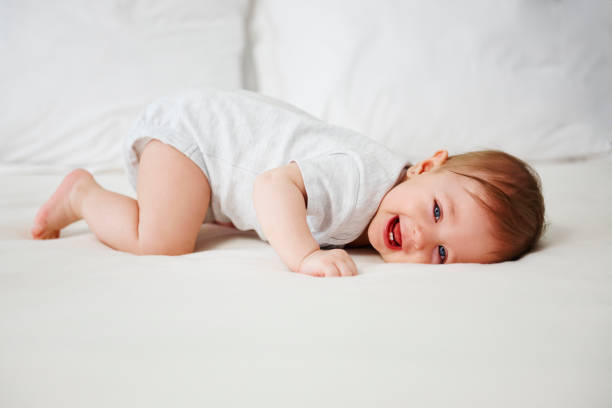 bebé juguetón divertirse en la cama - acostado boca abajo fotografías e imágenes de stock