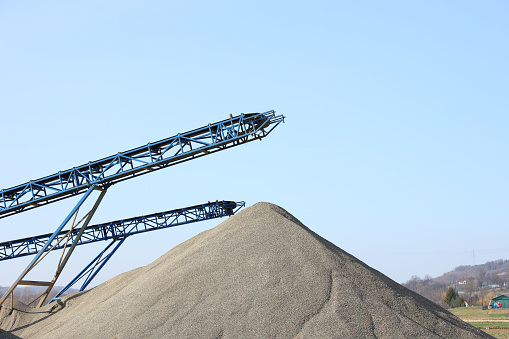 Elements of equipment for the extraction and sorting of rubble. Production of construction materials. Metal construction for working with stone and rocks. Slag of gravel under the conveyor belt.