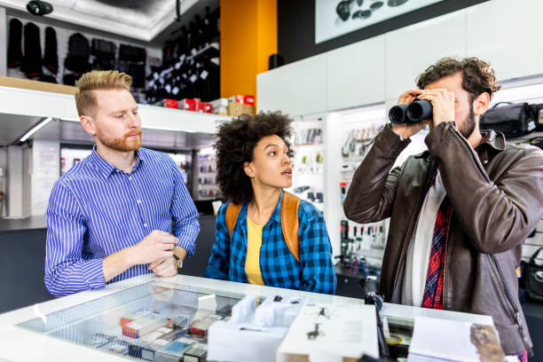 istock Young couple testing out a set of binoculars with a camera store clerk helping them 1138811216